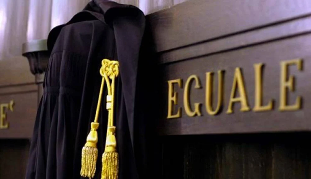 Toga da magistrato appesa in aula di tribunale, con la scritta "La legge è uguale per tutti" in evidenza