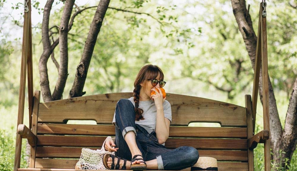 Donna con borsa ecologica con frutta in campagna