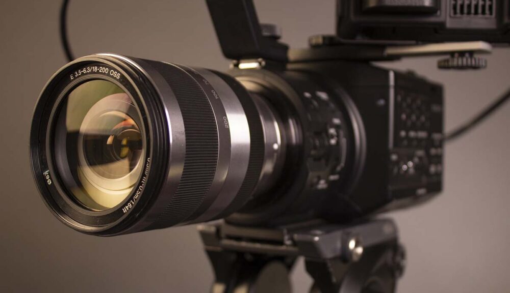 Macchina da presa professionale con obiettivo zoom montata su cavalletto, pronta per le riprese cinematografiche in studio.