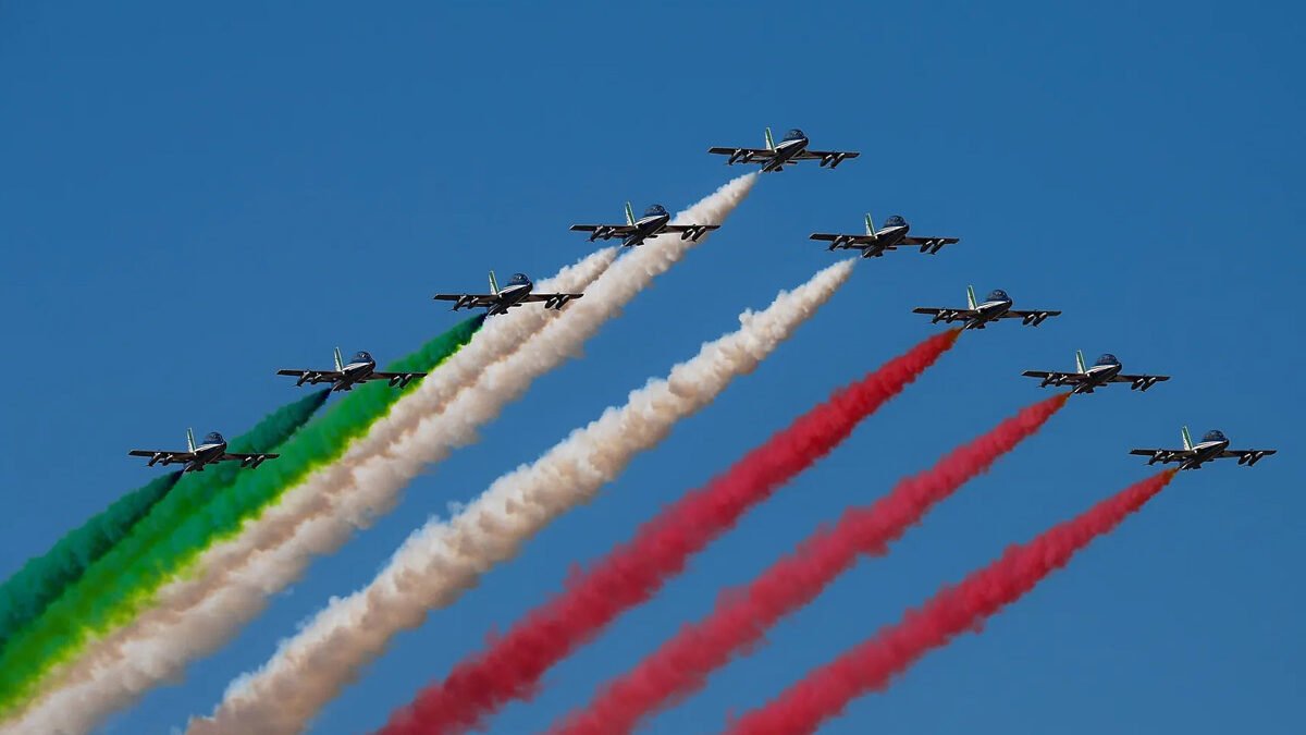 Aerei della Pattuglia Acrobatica Frecce Tricolori in volo con scie verde, bianca e rossa nel cielo azzurro per la Festa della Repubblica del 2 giugno.