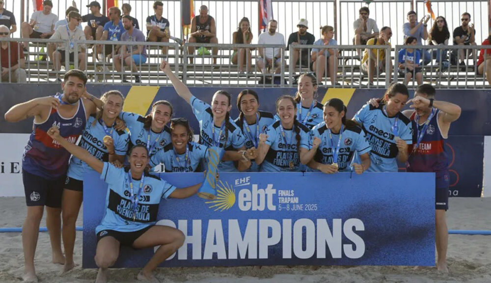La squadra femminile del Cats A.M. Team Almeria festeggia la vittoria alle EBT Finals 2025 di beach handball a Trapani, posando con il cartello 'Champions' sulla sabbia del Lido AC Life Style"