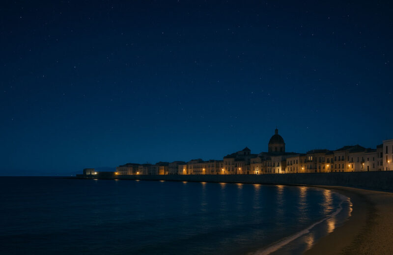 Veduta notturna della costa di Trapani con cielo stellato, edifici storici illuminati e riflessi sul mare calmo