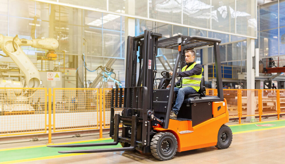 Operatore alla guida di un muletto elettrico in magazzino industriale automatizzato, simbolo di logistica efficiente e sostenibile.