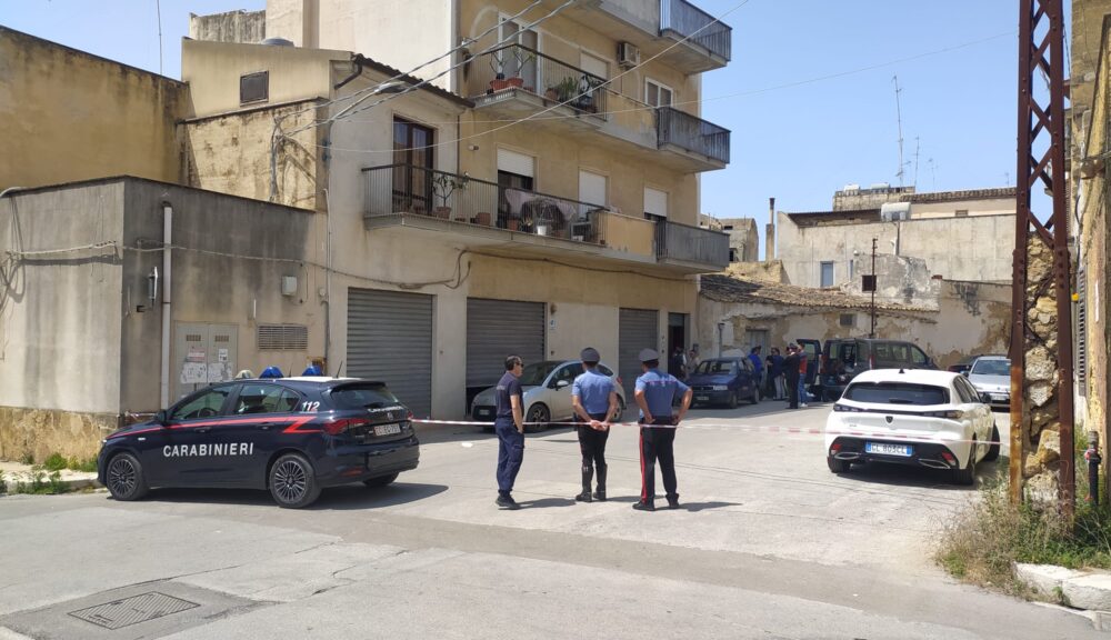 Scena del crimine a Castelvetrano con carabinieri e nastro di sicurezza davanti a una palazzina in via IV Aprile, luogo dell'omicidio-suicidio