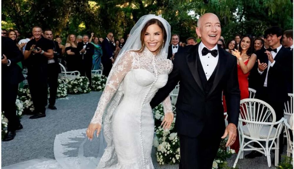 Jeff Bezos e Lauren Sanchez sorridenti dopo il matrimonio, camminano mano nella mano tra gli ospiti festanti in un elegante giardino addobbato con fiori bianchi.