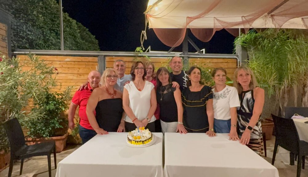 Gruppo di ex compagni durante una rimpatriata scolastica con torta celebrativa