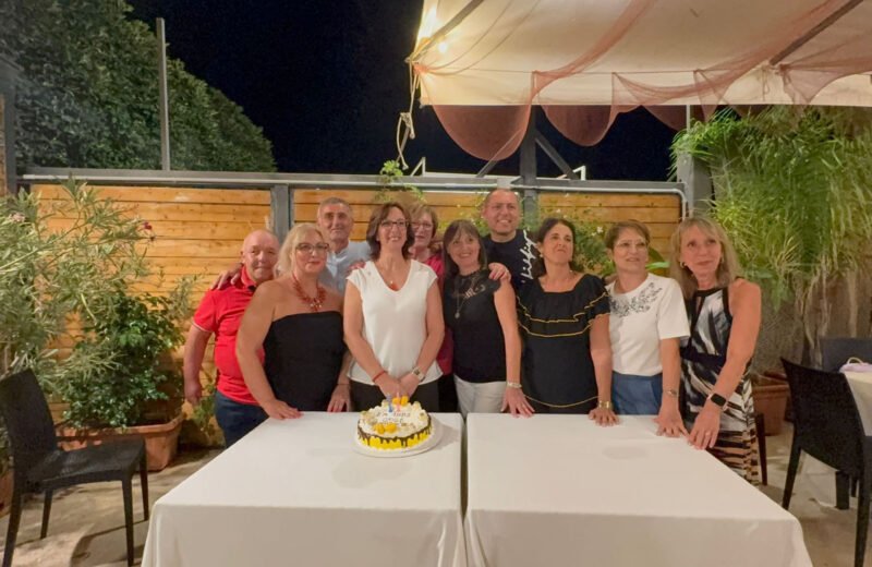 Gruppo di ex compagni durante una rimpatriata scolastica con torta celebrativa