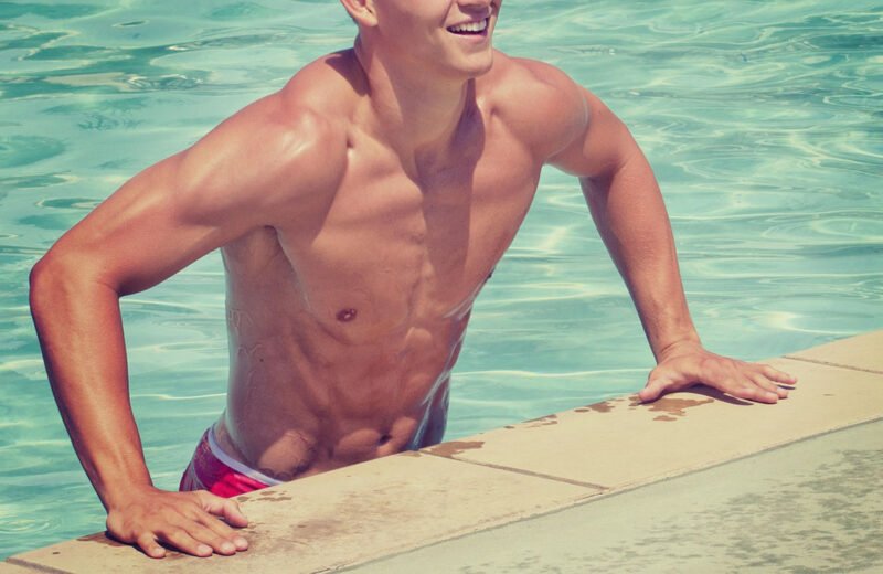 omo muscoloso che esce dalla piscina con addominali scolpiti