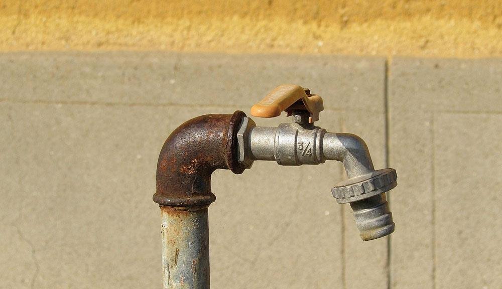 rubinetto chiuso arrugginito con sfondo murale