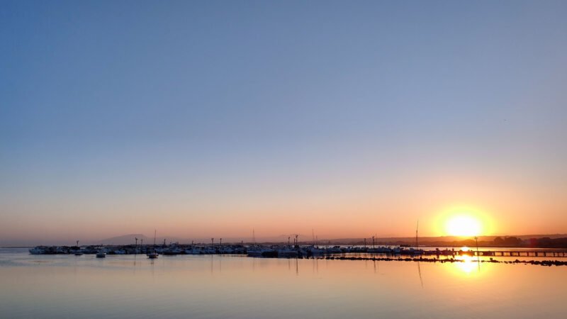 Tramonto sul mare con barche e riflessi dorati, fotografia di Peppe Piccolo intitolata “Il calar della sera a Marsala”