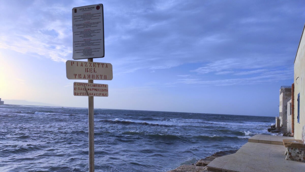 Piazzetta del Tramonto a Trapani al calar della sera con il mare mosso e il cielo blu